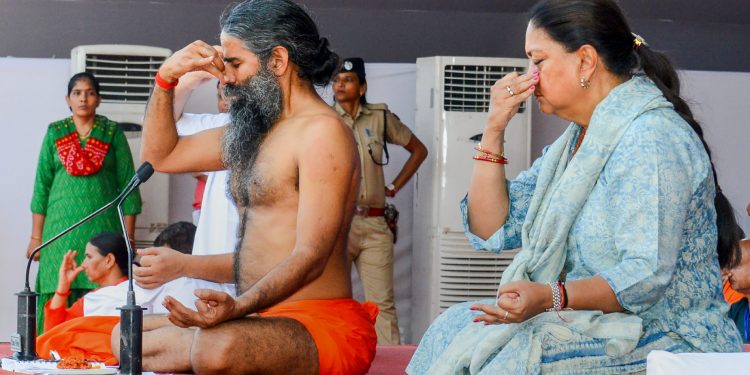 Kota: Yoga guru Ramdev Baba and Rajasthan Chief Minister Vasundhara Raje perform yoga during an event to set the Guinness World Record for 'The Largest Yoga Lesson' during the International Day of Yoga, in Kota on Thursday, June 21, 2018. (PTI Photo) (PTI6_21_2018_000114B)