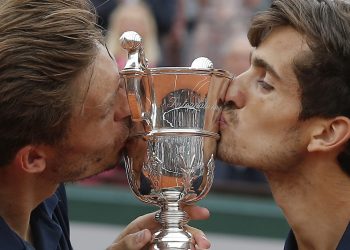 Pierre-Hughes Herbert (R) and Nicolas Mahut kiss the trophy as they celebrate winning the men’s doubles final at Roland Garros, Saturday