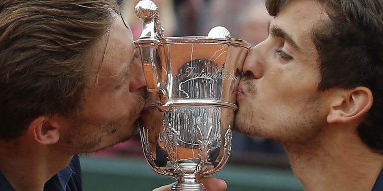 Pierre-Hughes Herbert (R) and Nicolas Mahut kiss the trophy as they celebrate winning the men’s doubles final at Roland Garros, Saturday