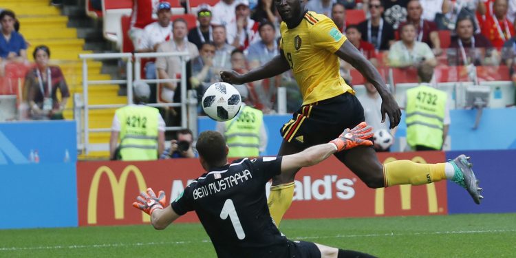 Belgium’s Romelu Lukaku tucks the ball past Tunisian goalkeeper Farouk Ben Mustapha to score his side’s third goal, Saturday 