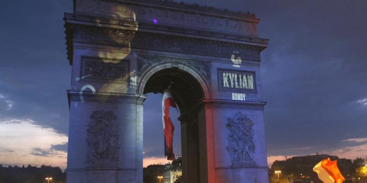 Kylian Mbappe's name is projected onto the Arc de Triomphe in Paris as fans invade the Champs-Elysees Avenue after France’s World Cup triumph, Sunday