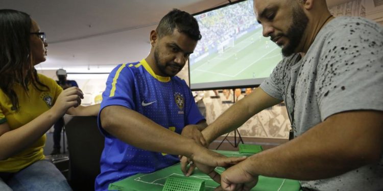 Carlos Junior (in blue) takes the help from interpreter Helio Fonseca de Araujo (R) during the Brazil versus Mexico match, Monday
