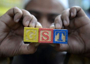 An Indian consumer goods trader shows letters GST representing "Goods and Services Tax" (GST)at his shop in Hyderabad on August 3, 2016. 
Finance Minister Arun Jaitley said India was on the cusp of its biggest tax reform since independence ahead of a vote in parliament later August 3, on a new national sales tax. The Goods and Services Tax (GST) will replace a patchwork of central and state levies on goods and services and is one of Prime Minister Narendra Modi's biggest reforms since taking power in May 2014 . / AFP PHOTO / NOAH SEELAM
