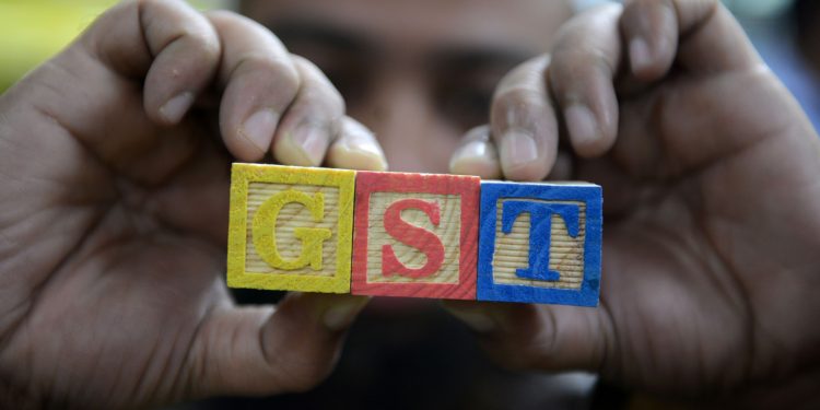 An Indian consumer goods trader shows letters GST representing "Goods and Services Tax" (GST)at his shop in Hyderabad on August 3, 2016. 
Finance Minister Arun Jaitley said India was on the cusp of its biggest tax reform since independence ahead of a vote in parliament later August 3, on a new national sales tax. The Goods and Services Tax (GST) will replace a patchwork of central and state levies on goods and services and is one of Prime Minister Narendra Modi's biggest reforms since taking power in May 2014 . / AFP PHOTO / NOAH SEELAM