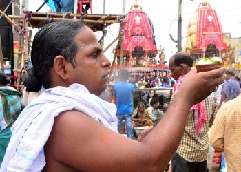 A devotee offers Rasagola to deities near their chariots in Puri, Wednesday. 