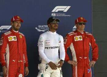 Lewis Hamilton (C) who earned pole position, Ferrari driver Kimi Raikkonen (R) who came in third and teammate Sebastian Vettel who earned the second best time, pose for photos after the qualifying session for the British Grand Prix, at the Silverstone racetrack,Saturday