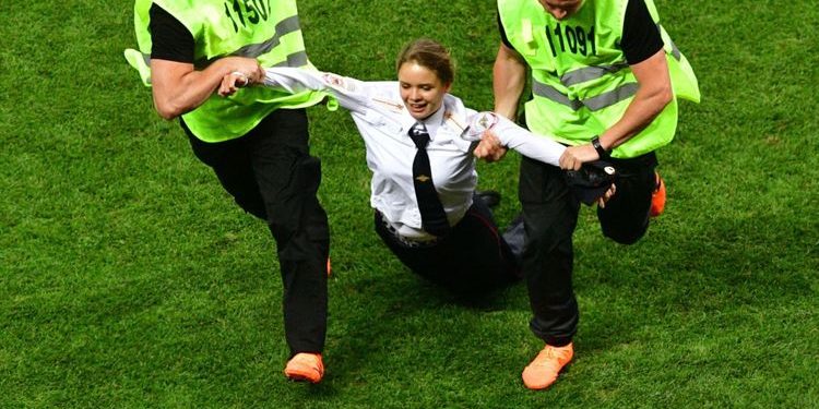 Security personnel drag away one of the persons who ran on to the pitch during the final of the World Cup