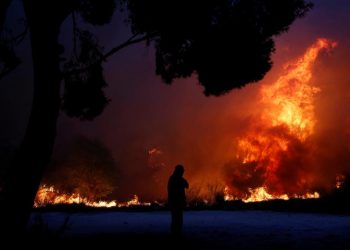 A man looks at the flames as a wildfire burns in the town of Rafina, near Athens. REUTERS/Costas Baltas