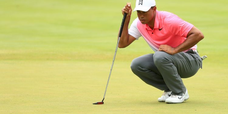 Tiger Woods inspects the lay of the green before taking his shot Friday