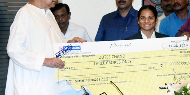 Chief Minister Naveen Patnaik hands a cheque of rupees three crore to Dutee Chand at the state Secretariat