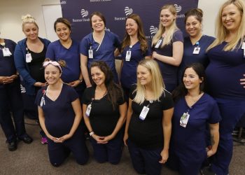 Most of the sixteen pregnant nurses who work together in the intensive care unit at Banner Desert Medical Center pose for a group photograph after attending a news conference where they all talked about being pregnant at the same time, with most of them due to give birth between October and January, Friday, Aug. 17, 2018, in Mesa, Ariz. (AP Photo/Ross D. Franklin)