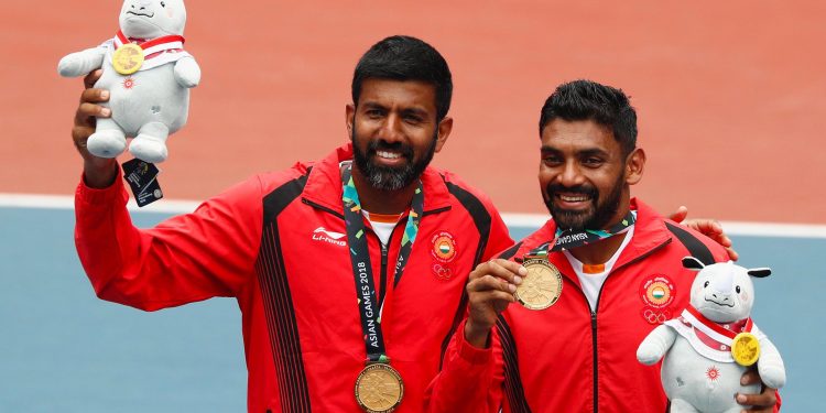 Gold medallists Rohan Bopanna and Divij Sharan celebrate with their medals and plush mascots.