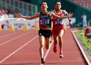 Japan’s Hiroto Inoue celebrates as he crosses the line to win the men’s marathon with Bahrain’s Elhassan Elabbassi trying to catch up 