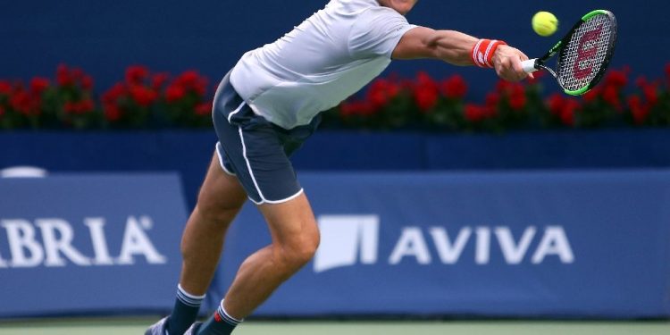 Milos Raonic stretched to hit a backhand during his first round match against David Goffin at Toronto, Monday