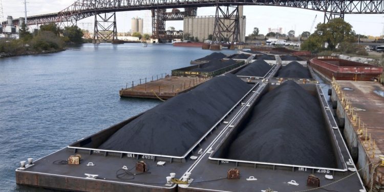 In this Oct. 25, 2013 photo, petroleum coke, or petcoke, is stored on barges on the Calumet River near the Chicago Skyway Bridge in Chicago. The grainy black byproduct of oil refining has been piling up along Midwest shipping channels and sparking a new wave of environmental concerns. The volume and size of petcoke piles has grown sharply _ especially in the Midwest. (AP Photo/Charles Rex Arbogast)
