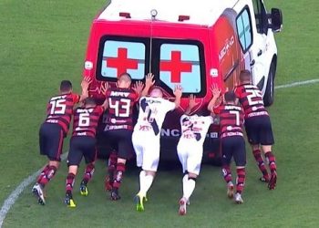 Players of both Flamengo and Vasco trying to push the ambulance which had broken down on the pitch while carrying an injured footballer