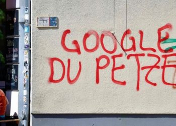 A woman sits next to anti-Google graffiti in Kreuzberg