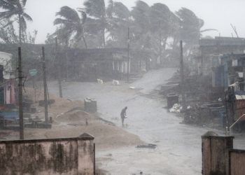 A man stands near Arjipalli beach during rain and strong winds caused by cyclonic storm named Titli, or Butterfly near Gopalpur on the Bay of Bengal coast, Ganjam district, eastern Orissa state, India, Thursday, Oct.11, 2018. The severe cyclone damaged mud huts and uprooted trees and electric poles Thursday in eastern India where authorities have moved nearly 300,000 people to higher ground. (AP Photo)
