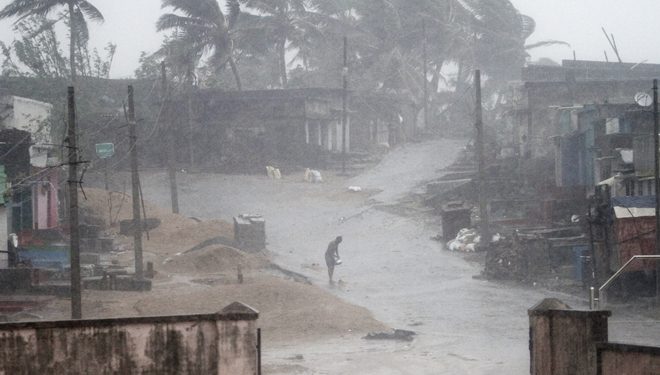 A man stands near Arjipalli beach during rain and strong winds caused by cyclonic storm named Titli, or Butterfly near Gopalpur on the Bay of Bengal coast, Ganjam district, eastern Orissa state, India, Thursday, Oct.11, 2018. The severe cyclone damaged mud huts and uprooted trees and electric poles Thursday in eastern India where authorities have moved nearly 300,000 people to higher ground. (AP Photo)