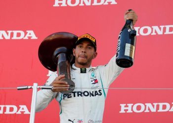 Lewis Hamilton, with the winner’s trophy on his shoulder, holds the champaign aloft while celebrating his victory at Suzuka, Sunday  