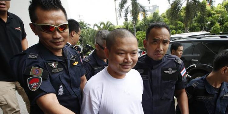 In this Thursday, July 20, 2017, Ex-monk Wirapol Sukphol is escorted by the Department of Special Investigation officials to the prosecutor's office in Bangkok, Thailand. A court in Thailand has sentenced Wirapol, a former Buddhist monk known for his jet-set lifestyle, to 16 years in prison for raping a 13-year-old girl who he also impregnated. (AP Photo/Sakchai Lalit)