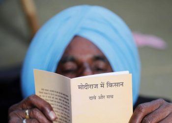 A farmer reads a book during a rally to protest soaring farm operating costs and plunging prices of their produce, in New Delhi, Friday.