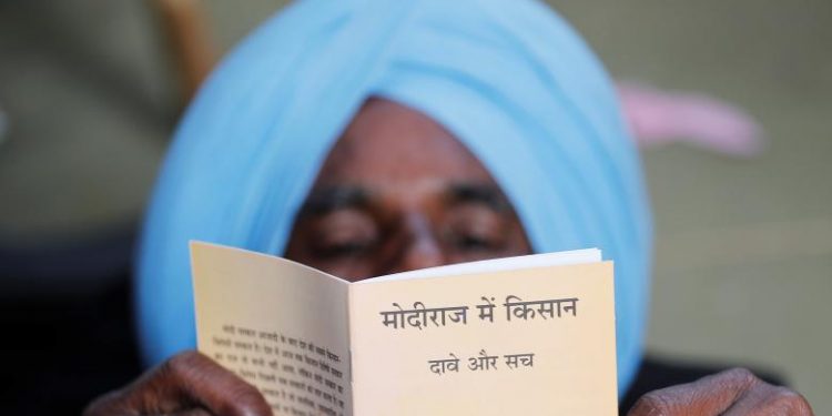 A farmer reads a book during a rally to protest soaring farm operating costs and plunging prices of their produce, in New Delhi, Friday.