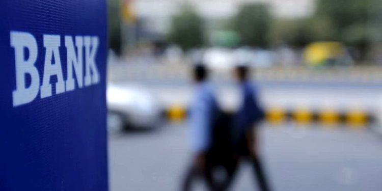 Commuters walk across a bank signage in Delhi (TWITTER)