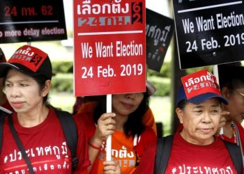 Thai pro-democracy activists hold placards as they gather outside the Royal Thai Army Club