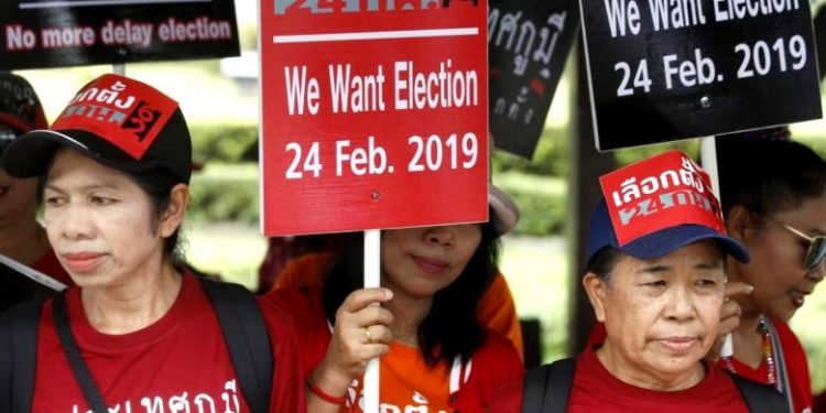 Thai pro-democracy activists hold placards as they gather outside the Royal Thai Army Club