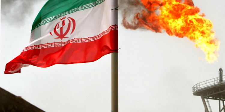 A gas flare on an oil production platform in the Soroush oil fields is seen alongside an Iranian flag in the Persian Gulf, Iran, July 25, 2005. (REUTERS)