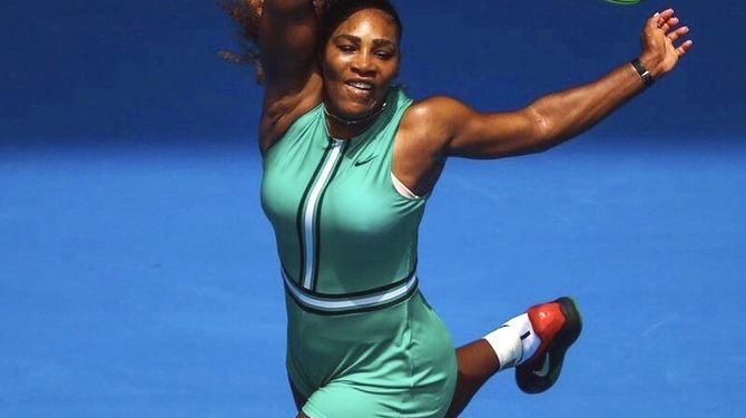 Serena Williams warmed up on Rod Laver Arena in a long, black raincoat which she discarded to reveal a figure-hugging, bottle green one-piece costume paired with fish-net compression stockings. (REUTERS)