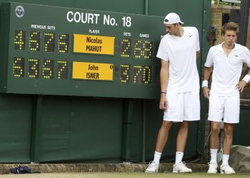 In this June 24, 2010, file photo, John Isner of the United States, left, and France's Nicolas Mahut pose for a photo next to the scoreboard following their epic men's singles match at the All England Lawn Tennis Championships at Wimbledon. The Australian Open and Wimbledon are finally doing what the U.S. Open has done for decades: figuring out a way to end a fifth set before it becomes another 26-24 slog or _ perish the thought _ 70-68. While some fans and others might still like the idea that a match could go on and on and on forever, or seemingly forever, players such as John Isner are thrilled about the change. (AP)
