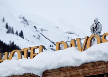 A Swiss police officer observes the surrounding area from atop the roof of the Davos Congress Hotel ahead of the World Economic Forum (WEF) annual meeting in Davos, Switzerland, Monday