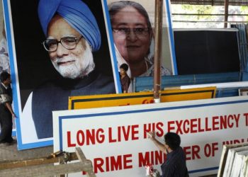 A painter prepares a welcome banner as portraits of former Prime Minister Manmohan Singh and Prime Minister Sheikh Hasina are moved in the background (Twitter)