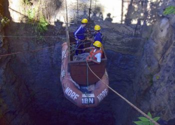 In this photo taken on December 30, 2018, Indian Navy divers go down in the mine with a pulley during rescue operations after 15 miners were trapped by flooding in an illegal coal mine in Ksan village in Meghalaya's East Jaintia Hills district of India. - Indian Navy and NDRF personnel went inside a 370-foot-deep mine, where 15 miners are trapped, to ascertain the water level inside on December 30, officials said. (Photo by - / AFP)