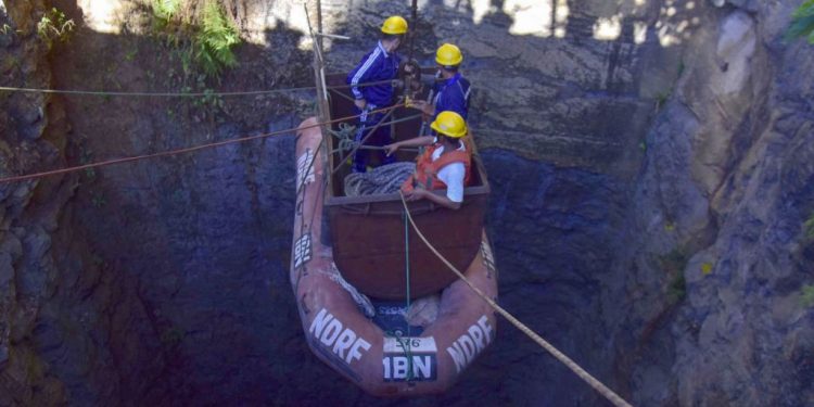 In this photo taken on December 30, 2018, Indian Navy divers go down in the mine with a pulley during rescue operations after 15 miners were trapped by flooding in an illegal coal mine in Ksan village in Meghalaya's East Jaintia Hills district of India. - Indian Navy and NDRF personnel went inside a 370-foot-deep mine, where 15 miners are trapped, to ascertain the water level inside on December 30, officials said. (Photo by - / AFP)
