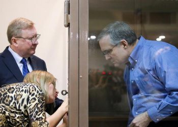 Former US marine Paul Whelan, who was detained by Russia's FSB security service on suspicion of spying, speaks with lawyers while standing in a defendants' cage before a court hearing in Moscow