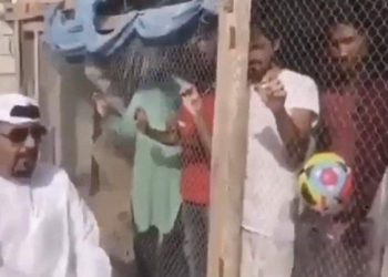 The man poses with Indian fans locked up in a cage with a football