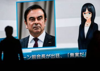 Pedestrians pass by a television screen showing a news program featuring former Nissan Chairman Carlos Ghosn in Tokyo on Tuesday. (AFP)