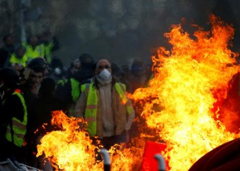 Protesters wearing yellow vests are seen behind a fire as they attend a demonstration of the "yellow vests" movement in Angers, France, January 19, 2019. (REUTERS)