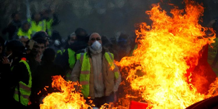 Protesters wearing yellow vests are seen behind a fire as they attend a demonstration of the "yellow vests" movement in Angers, France, January 19, 2019. (REUTERS)