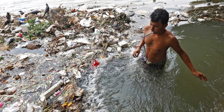 A man brushes his teeth as he stands in the polluted water of Ganges river in Kolkata, India. (REUTERS)