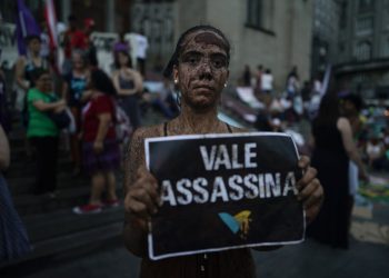 An activists covered in mud poses with a sign that reads "Vale assassin" during a demonstration on the front steps of Sao Paulo's Cathedral, Brazil, Friday, Feb. 1, 2019. (AP)