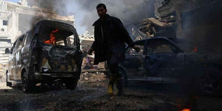 A civil defence member works amid burning vehicles at a site hit by airstrikes in the rebel held besieged Douma neighbourhood of Damascus, Syria, February 26, 2017 (REUTERS)