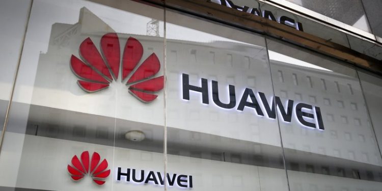 In this Jan. 29, 2019, file photo, the logos of Huawei are displayed at its retail shop window reflecting the Ministry of Foreign Affairs office in Beijing. (AP)