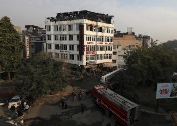 Onlookers stand on the rooftop of a building as they look at a hotel where a fire broke out in New Delhi, India, February 12, 2019. (REUTERS)