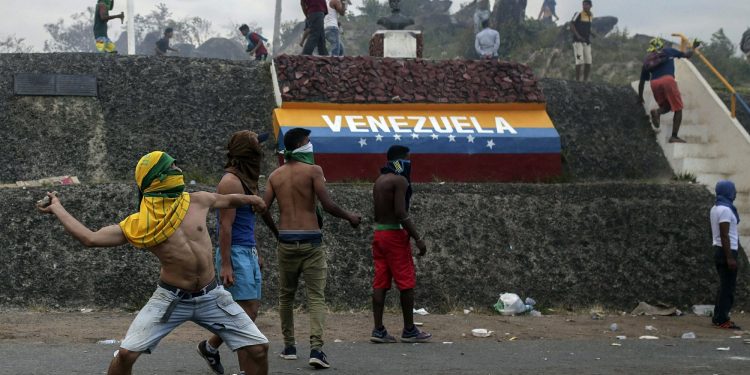 Venezuelan demonstrators throw stones during clashes with authorities, at the border between Brazil and Venezuela, Saturday, Feb.23, 2019. Tensions are running high in the Brazilian border city of Pacaraima. Thousands remained at the city's international border crossing with Venezuela to demand the entry of food and medicine.(AP)