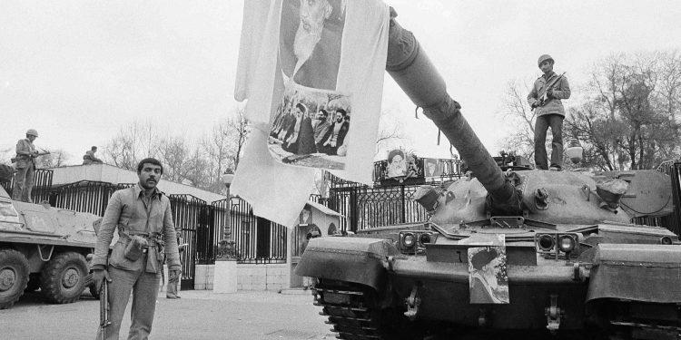 FILE - In this Feb. 13, 1979 file photo, a large picture of Ayatollah Khomeini hangs from tank gun barrel in front of Niavaran Palace in Tehran, Iran. Forty years ago, Iran's ruling shah left his nation for the last time and an Islamic Revolution overthrew the vestiges of his caretaker government. The effects of the 1979 revolution, including the takeover of the U.S. Embassy in Tehran and ensuing hostage crisis, reverberate through decades of tense relations between Iran and America. (AP)