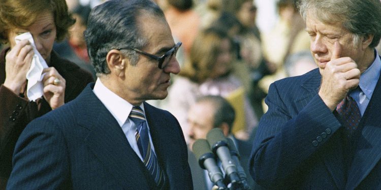 FILE - In this Nov. 15, 1977 file photo, then-first lady Rosalyn Carter, left, Shah Mohammad Reza Pahlavi, center, and then U.S. President Jimmy Carter, right, react to wafting tear gas as pro- and counter-shah demonstrators clash with police outside of the White House during a ceremony. Dozens would be injured in the violence. Forty years ago, Iran's ruling shah left his nation for the last time and an Islamic Revolution overthrew the vestiges of his caretaker government. The effects of the 1979 revolution, including the takeover of the U.S. Embassy in Tehran and ensuing hostage crisis, reverberate through decades of tense relations between Iran and America. (AP)